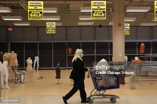 Patti Naleck pushes a cart filled with a mannequin through the Sears store in Woodfield Mall on Nov. 11 before it permanently closes this weekend in...