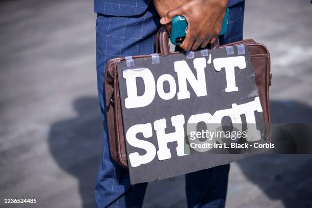 Wearing a suit and holding a briefcase that says Don't Shoot. Protesters took to the streets across America killing of George Floyd at the hands of a...