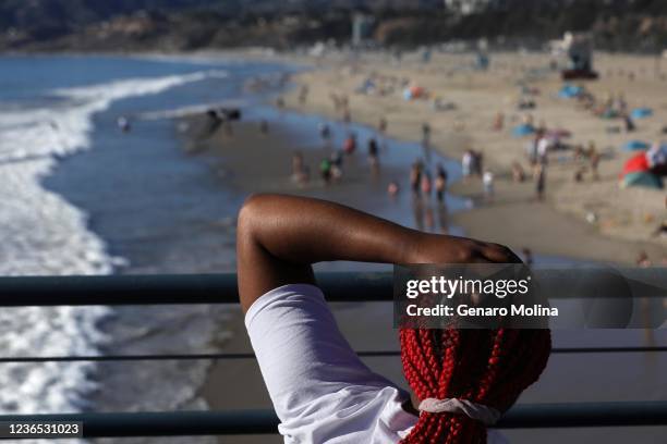 Jade Smith from Memphis, Tenn., deals with the heat while taking in the scene as temperatures hit 81 degrees this afternoon in Santa Monica on...