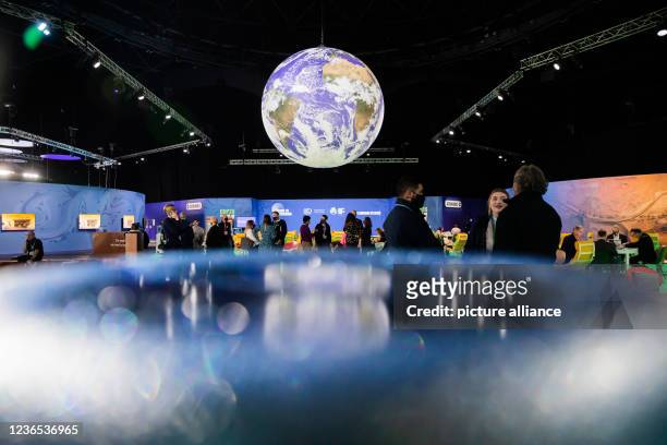 November 2021, United Kingdom, Glasgow: People are standing under a globe at the UN Climate Change Conference COP26. For two weeks in Glasgow, around...