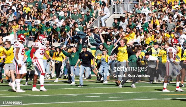 Oklahoma Sooners players walk away as Baylor Bears fans storm the field with time left on the clock in the second half at McLane Stadium on November...