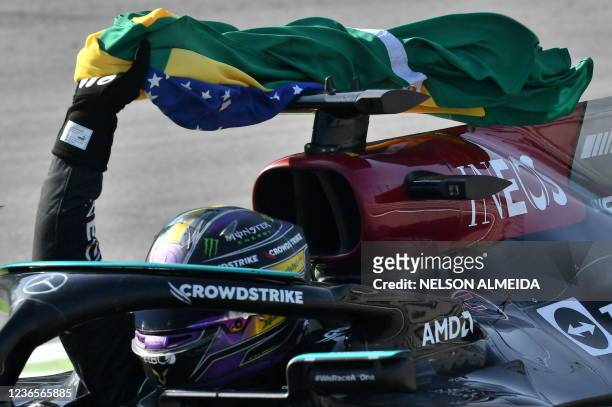 Mercedes' British driver Lewis Hamilton celebrates with a Brazilian flag after winning Brazil's Formula One Sao Paulo Grand Prix at the Autodromo...