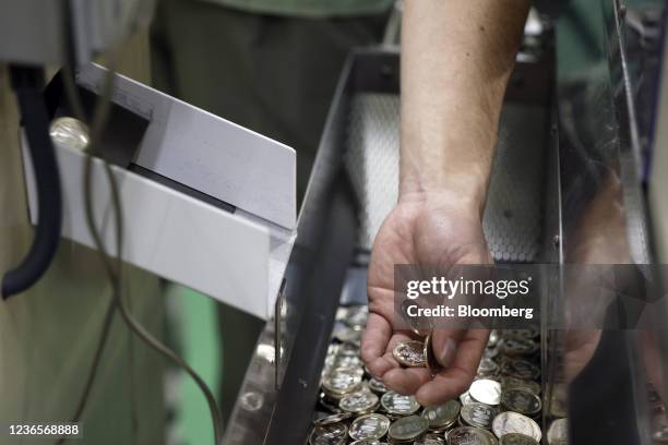 An employee inspects a newly-stamped Japanese 500 yen coin during the production at a Japan Mint factory in Saitama, Japan, on Thursday, Nov. 11,...