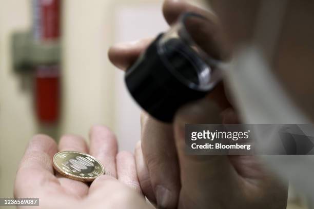 An employee inspects a newly-stamped Japanese 500 yen coin during the production at a Japan Mint factory in Saitama, Japan, on Thursday, Nov. 11,...