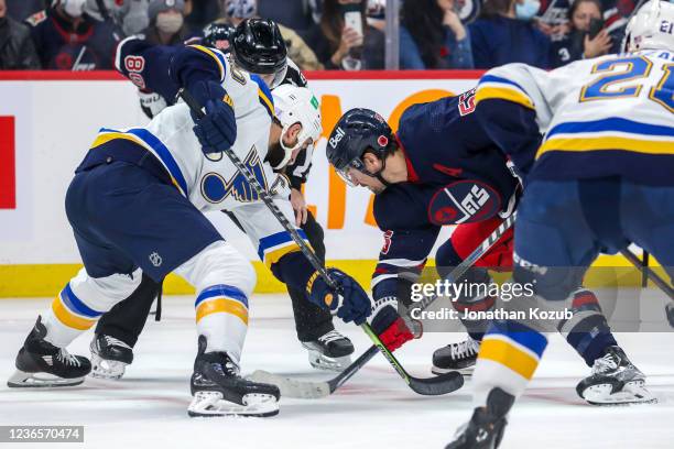 Ryan O'Reilly of the St. Louis Blues and Mark Scheifele of the Winnipeg Jets take a second period face-off at Canada Life Centre on November 09, 2021...