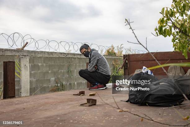 Young man waiting for the next train to Serbia. Refugees and migrants are seen at the railway junction and the old abandoned train carriages living...