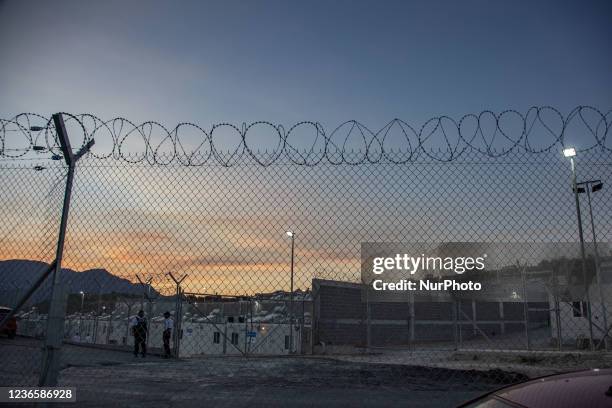 Barbed-wire fence protecting the camp from outsiders. Evening sunset time outside of the barbed wire fence of the new camp for asylum seekers. A New...