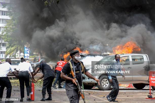 People extinguish fire on cars caused by a bomb explosion near Parliament building in Kampala, Uganda, on November 16, 2021. - Two explosions hit...