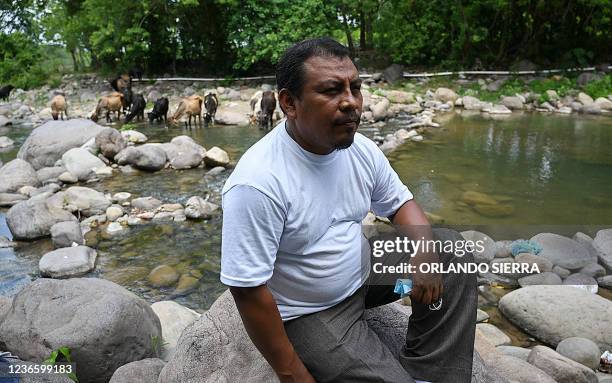 Honduran environmentalist Juan Lopez sits on a rock as he watches the Guapinol river on the outskirts of Tocoa, Colon department, Honduras, on...