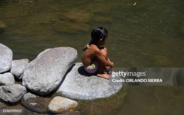 Girl sits on a rock as she watches the waters of the Guapinol river on the outskirts of Tocoa, Colon department, Honduras, on September 28, 2021. -...