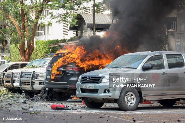 Cars are on fire after a bomb explosion near the Parliament building in Kampala, Uganda, on November 16, 2021. - Two explosions hit Uganda's capital...