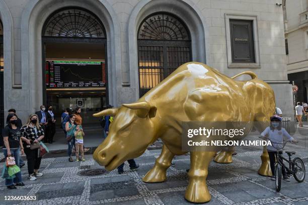 People pose next to the "Charging Bull" replica statue in front of Sao Paulo's Stock Exchange headquarters, in Sao Paulo, Brazil, on November 16,...