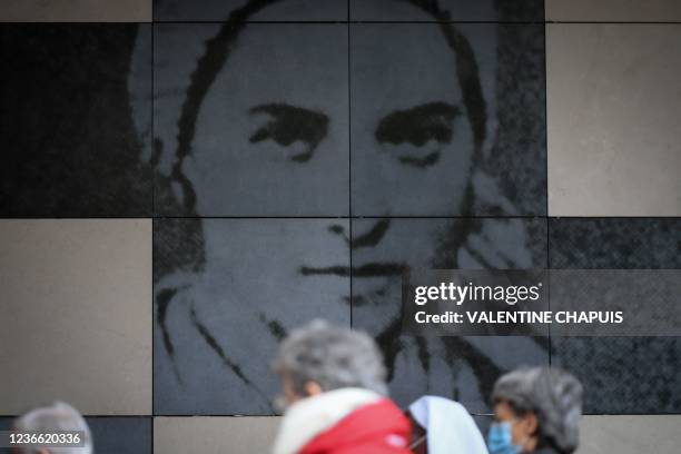 Clerics walk in front of a portrait of Bernadette Soubirous at the hemicycle, in Lourdes, southwestern France, on November 17, 2021. - The general...