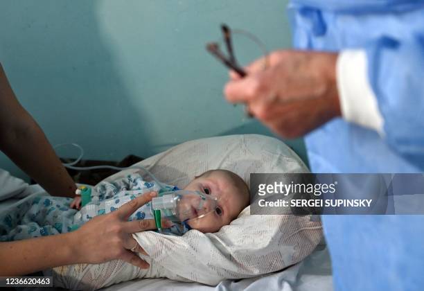 Woman holds an oxygen mask over the face of her baby suffering from the coronavirus disease in a ward of a children's hospital in Kiev on November...