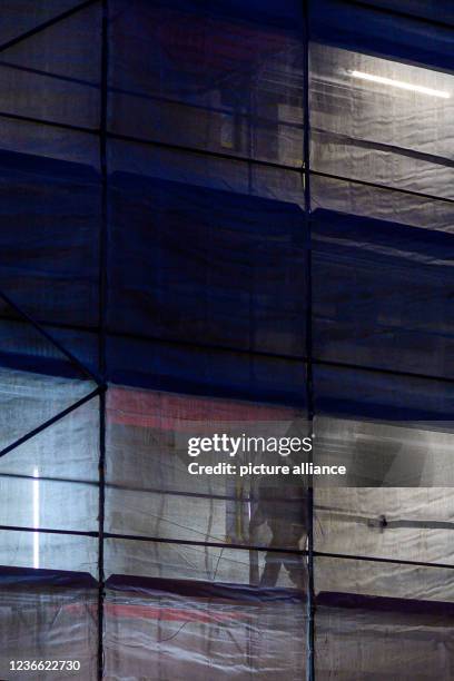 November 2021, Saxony-Anhalt, Magdeburg: A scaffolding covered with a tarpaulin shines brightly at nightfall at the cathedral. Under the brightly...