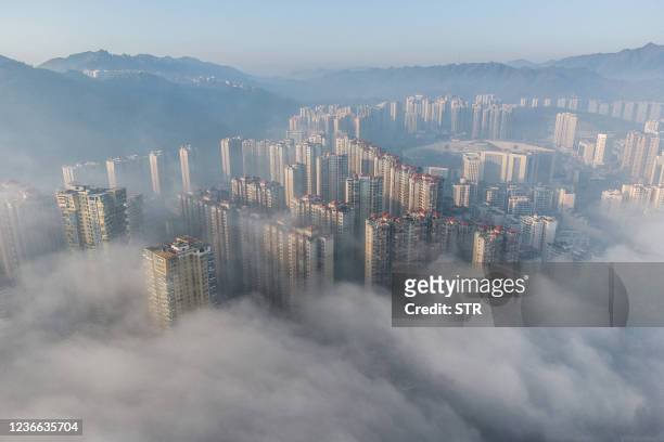 This aerial photograph shows buildings shrouded in morning fog in Bijie, China's southwestern Guizhou province, on November 18, 2021. - China OUT /...