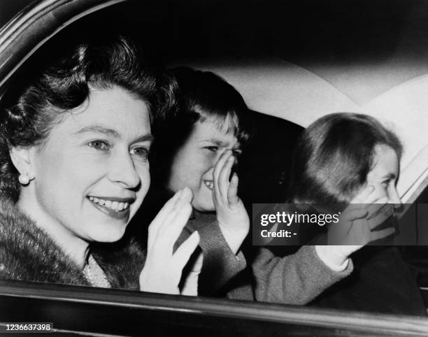 Queen Elizabeth II, Prince Andrew and Princess Anne wave to the crowd, on December 24, 1965 in London as they leave the Buckingham Palace by car to...