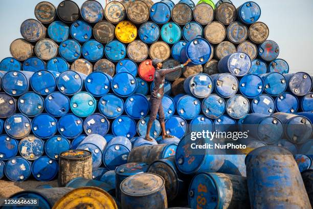 Worker stack empty oil drums for recycling at a warehouse in Narayanganj on November 4, 2021.