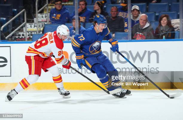 Tage Thompson of the Buffalo Sabres controls the puck against Elias Lindholm of the Calgary Flames during an NHL game on November 18, 2021 at KeyBank...