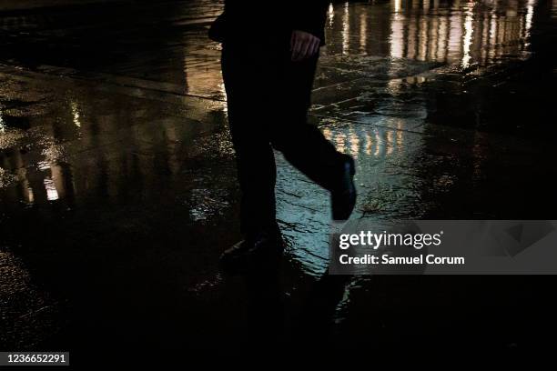 Man walks past the U.S. Capitol Building reflected in a puddle as Democrats in the House of Representatives attempt to hold a vote on the Build Back...