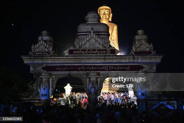 This photo taken on November 17, 2021 shows people next to a giant Buddha statue as they take part in the Tazaungdaing festival, also known as the...