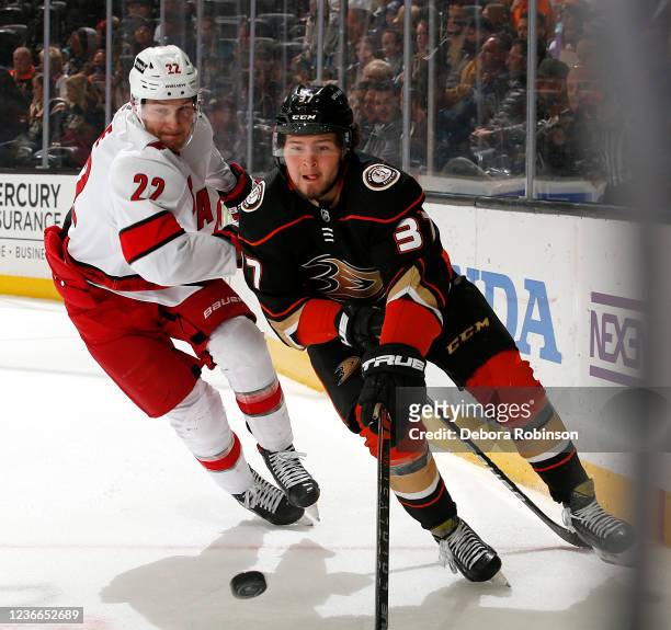 Mason McTavish of the Anaheim Ducks skates with the puck with pressure from Brett Pesce of the Carolina Hurricanes during the game at Honda Center on...