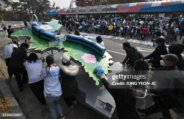 Pro-unification activists set up an installation showing trains on the Korean Peninsula during a rally urging the South Korean government to connect...