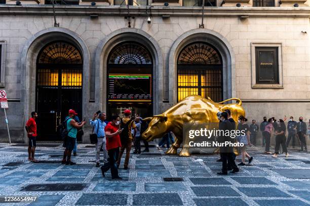 People pose next to the &quot;Charging Bull&quot; replica statue in front of Sao Paulo's Stock Exchange headquarters, in Sao Paulo, Brazil, on...