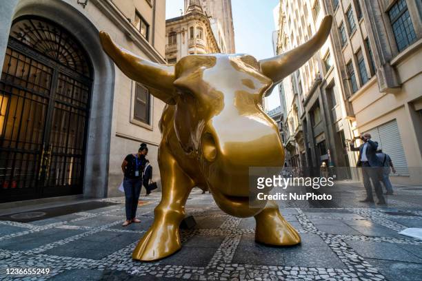 People pose next to the &quot;Charging Bull&quot; replica statue in front of Sao Paulo's Stock Exchange headquarters, in Sao Paulo, Brazil, on...