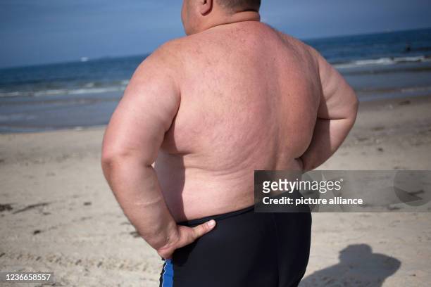 September 2021, Poland, Swinemünde: An overweight man stands on the beach. Photo: Fernando Gutierrez-Juarez/dpa-Zentralbild/ZB