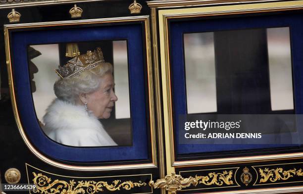 Britain's Queen Elizabeth II is pictured through a carriage window as she arrives back at Buckingham Palace after her speech in Parliament for the...