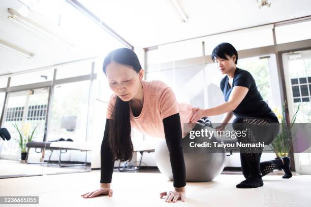 woman works out with a fitness ball - push up japanese stock-fotos und bilder