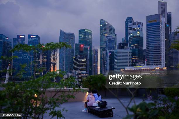 Young couple sits on a rooftop and take in a view of Singapore's central business district skyline, Singapore, Friday, 19 November 2021.