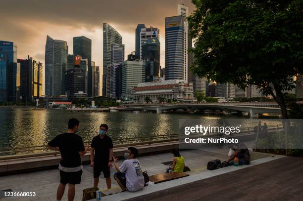 People relax along the waterfront of the Marina Bay area of Singapore with the central business district skyline in the background, in Singapore,...