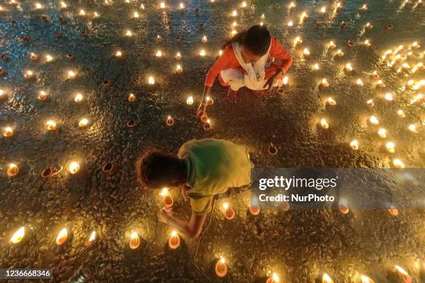 Mother and son is seen lighting oil lamps on the occasion of Dev Deepavali in Kolkata , India , on 19 November 2021 . Dev Deepavali is a Hindu...