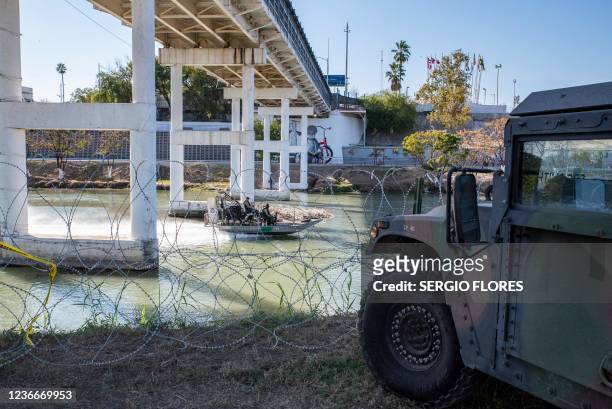 Customs and Border Patrol boat travels past razor wire and a military vehicle down the Rio Grande river on November 19, 2021 in Eagle Pass, Texas. -...
