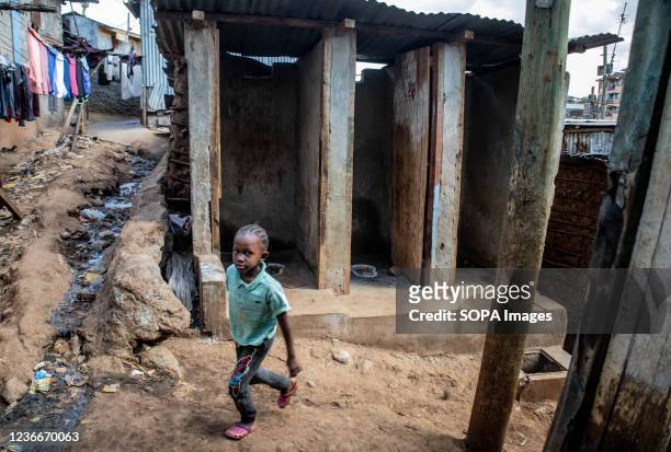 Young girl walks past abandoned toilets in Kibera Slums. World Toilet Day is an official United Nations international observance day on 19 November...