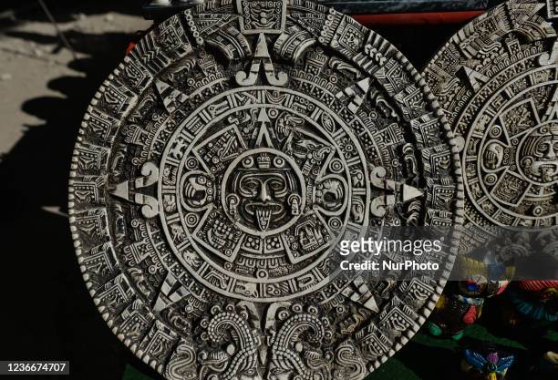 Aztec calendar of Mayan or Aztec vector hieroglyph signs and symbols on display at a stand with locally made gifts and souvenirs seen next to the...