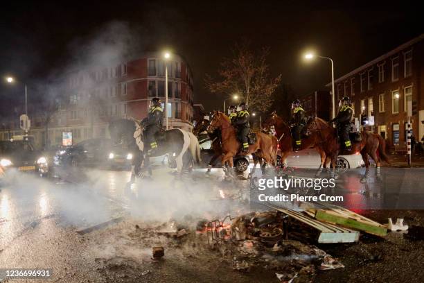 Police officers on horses patrol the streets of The Hague as riots erupt amid new COVID-19 restrictions on November 20, 2021 in The Hague,...