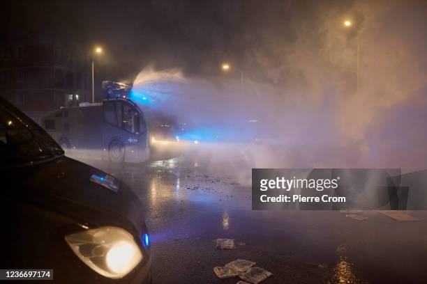 Water cannon extinguishes bycicles and scooter set ablaze by a mob as riots erupt amid new COVID-19 restrictions on November 20, 2021 in The Hague,...