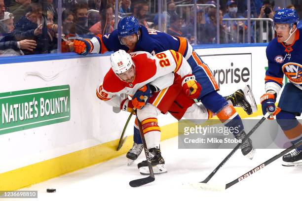 Dillon Dube of the Calgary Flames is checked by Grant Hutton of the New York Islanders during the second period at UBS Arena on November 20, 2021 in...
