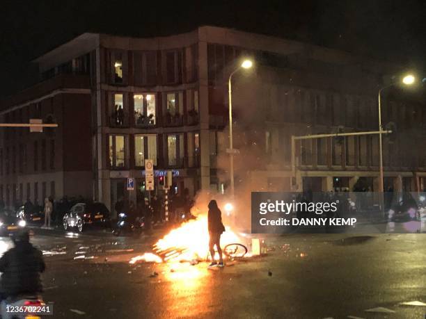 Man walks in front of a fire in a street of The Hague during a demonstration against the Dutch government's coronavirus measures, on November 20,...