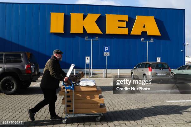 Man with a shopping trolley and a dog passes by the Ikea shop in Krakow, Poland on November 20, 2021.