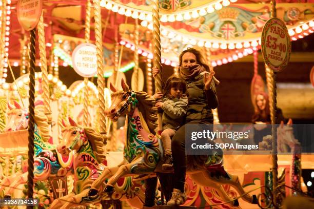 Mother seen going on the Merry-go-round with her baby girl. As Christmas approaches, various locations in London have set up Christmas markets for...