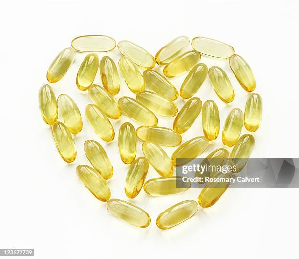 fish oil capsules placed to create heart symbol. - fish oil ストックフォトと画像