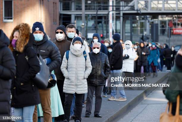 People wearing face masks stand in a reportedly 700-meter-long queue to get vaccinated in the Philharmonic Hall "Elbphilharmonie" in the northern...