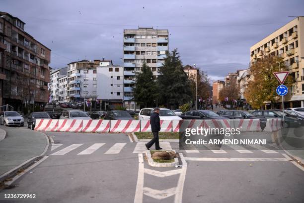Kosovo Albanian man walks along a barricade next to the Ibar river bridge in the town of Mitrovica, on November 9, 2021. - In Kosovo's Mitrovica,...