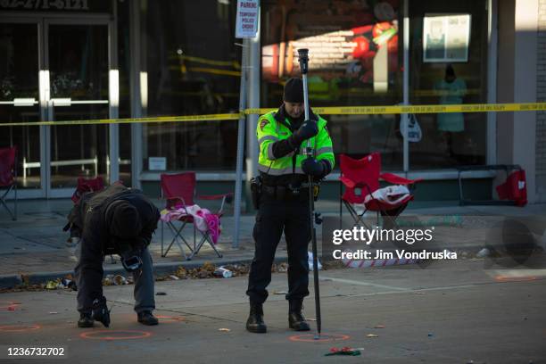 Police measure orange markers of debris left following a driver plowing into the Christmas parade on Main Street in downtown November 22, 2021 in...