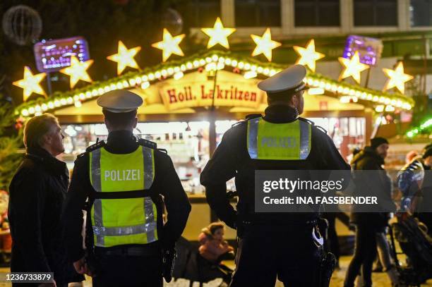 Police officers stand in fornt of a sweets booth at the Christmas market in Dortmund, western Germany on November 22, 2021. - Some of the German...