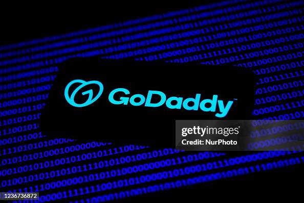 GoDaddy logo displayed on a phone screen and binary code displayed on ...